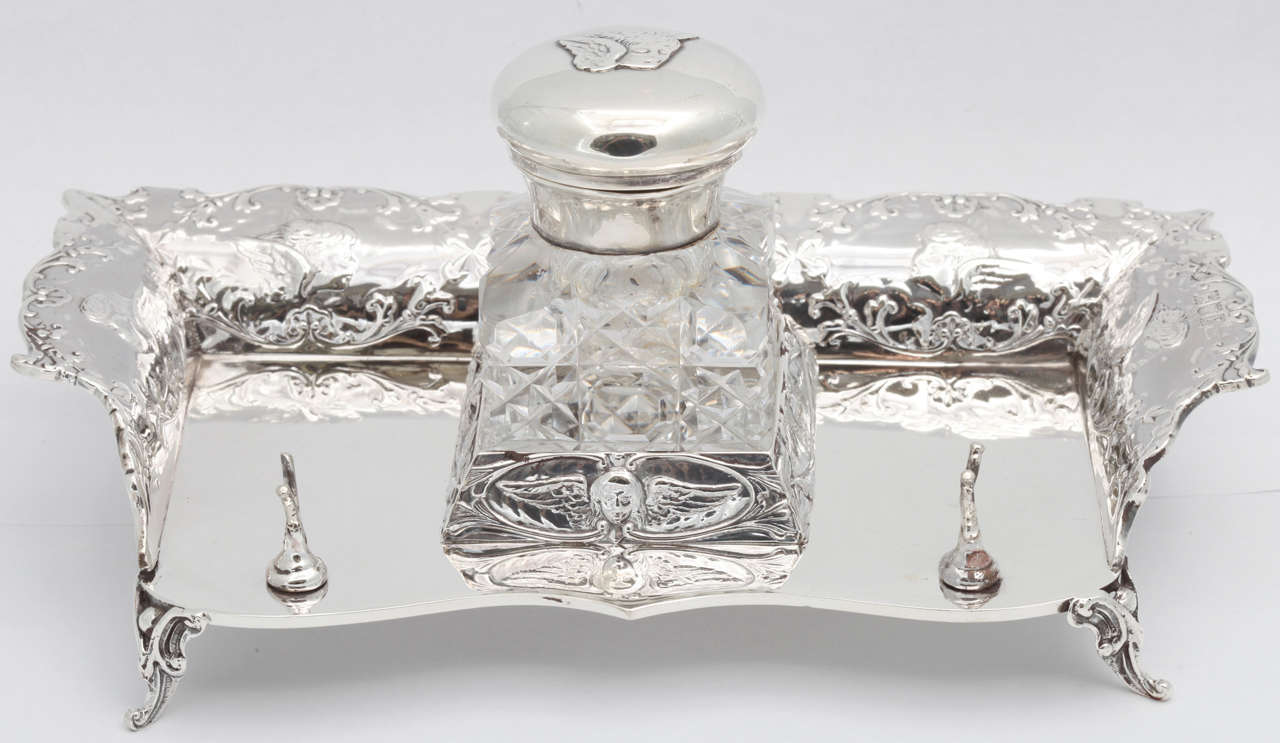 Outstanding, Victorian, sterling silver, footed inkstand with sterling silver-mounted crystal inkwell, London, 1901, William Comyns -  maker. Designed with Joshua Reynolds' cherubs motif. Motif is on the sterling silver inkstand and continued on the