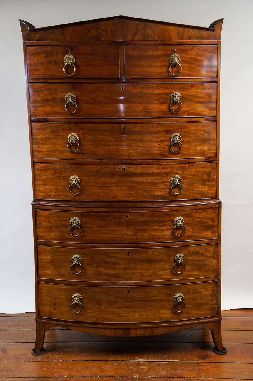 Stunning English c. 1810 late George III, early Regency period mahogany bow-front chest on chest of significant size having pointed neoclassical cornice with acroteria corners below eight drawers with original large finely cast brass lion's head