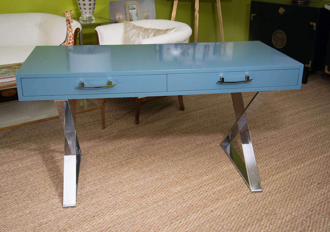 A very striking campaign style desk attributed to Milo Baughman with two drawers lacquered in a beautiful blue, raised on chrome x-form legs.  This piece will add star quality to any room.