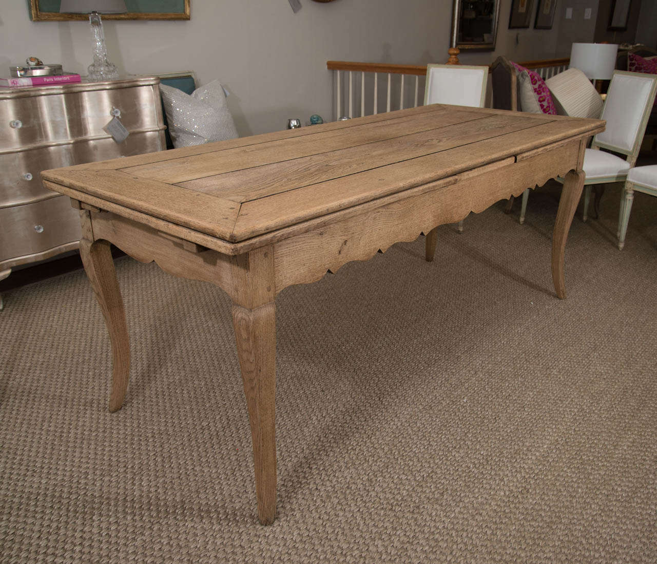 A bleached oak extension table with a scalloped apron.  The table seats 8 without opening the extensions.  The length as pictured is 76.5