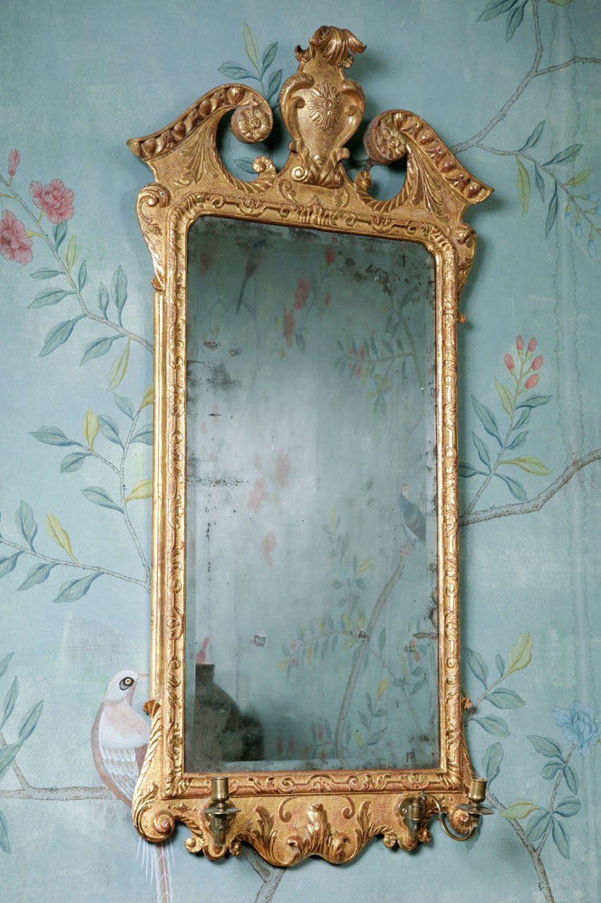 A splendid, good size, 18th century George II carved and gilded mirror. Interestingly the original gilding has been retained and is brighter and more luminous than re-gilded mirrors of this type. The upper part carved profusely with a broken arched