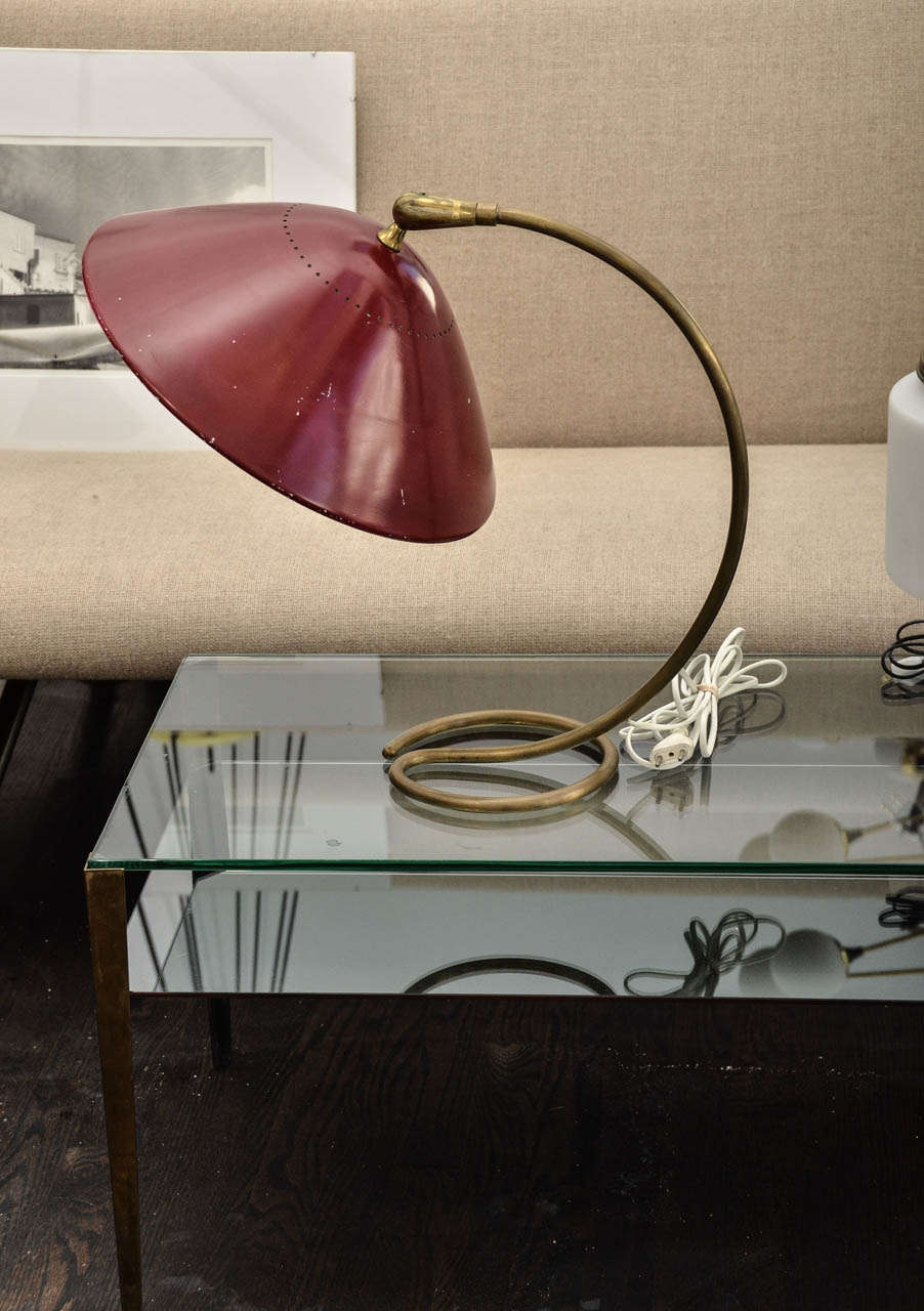 Italian adjustable table lamp by Stilnovo.  A red adjustable shade hold by a brass bent arm.
