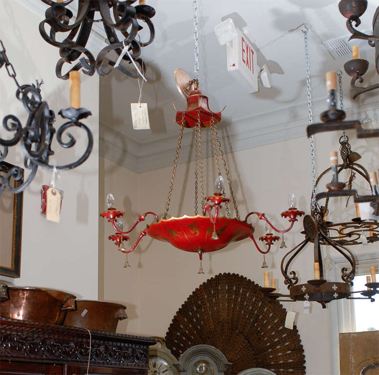 An English red tole Chandelier with Chinoiserie decor, gold figures and bells. This English light fixture is made of a red basket decorated with gilded chinoiserie motifs, to which scrolled arms are attached. The ensemble is connected to the pagoda