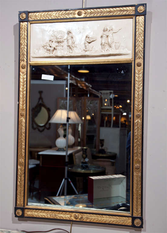 French trumeau mirror, 20th century, the cream painted with figural-decorated panel over a rectangular glass, surmounted by an ebonized and gilded frame, lovely carving of feather and patera.