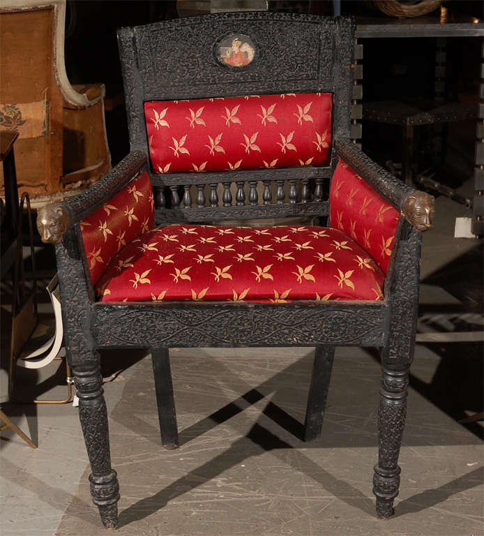 Pair of Anglo Indian ebonized and intricately carved armchairs with brass lion handles and inset paintings