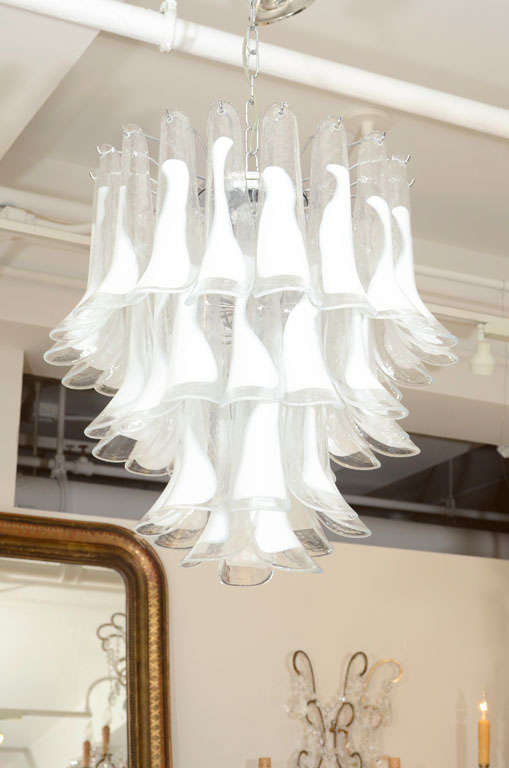 Individually sculpted clear and white hand blown murano glass petals or feathers make up this elegant chandelier.  Each hand made glass piece is partly covered by an opaque white color over transparent glass. The opacity of the color, allows the
