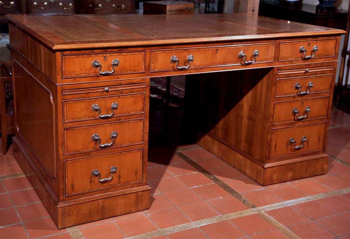 This Classic English style desk features a file drawer in the left-hand pedestal, a modern convenience not found in an antique desk. The three-piece, gold tooled tan leather and tulipwood crossbanding set this desk apart from many of today's modern,