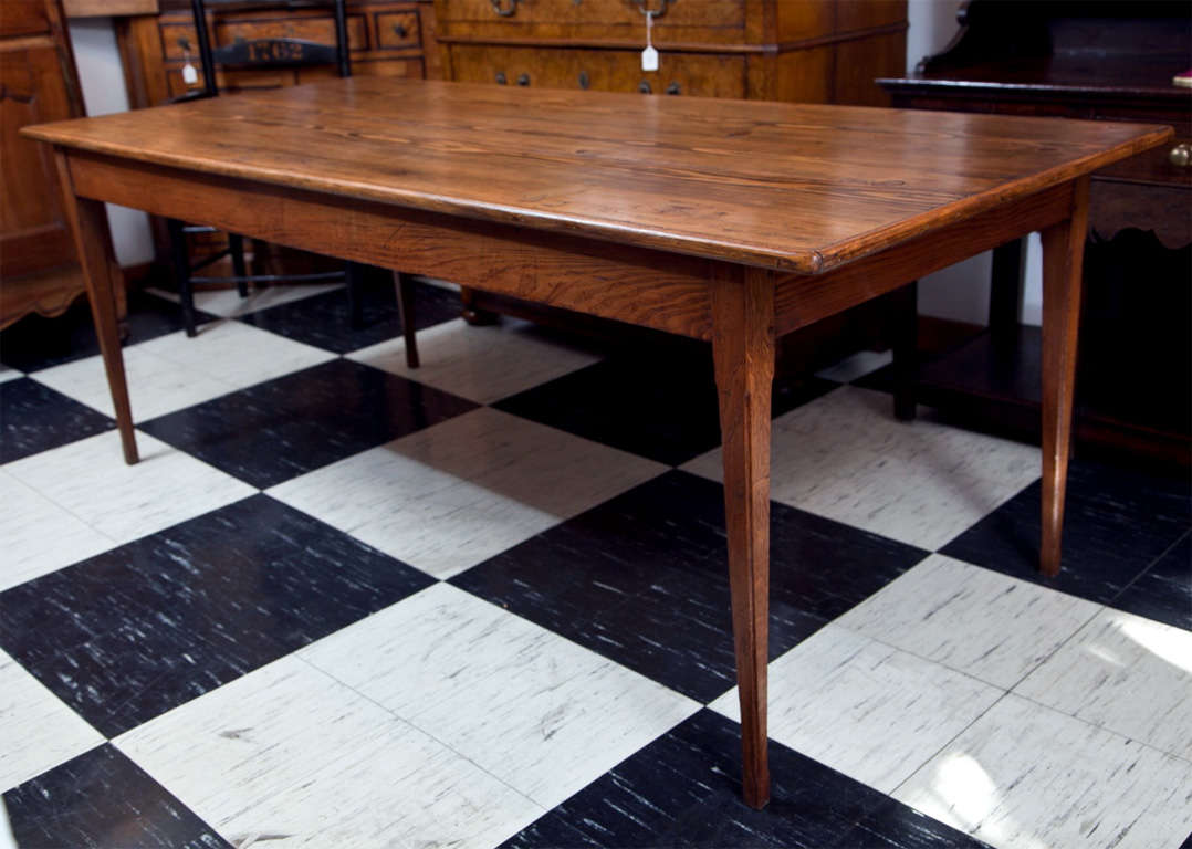 This pine farm table has a delicate Silhouette as it rests on narrow, chamfered legs, belying its utilitarian roots. The top grain, in more of a spruce appearance, has a deep grain pattern that is repeated in the apron, while the narrow frame that
