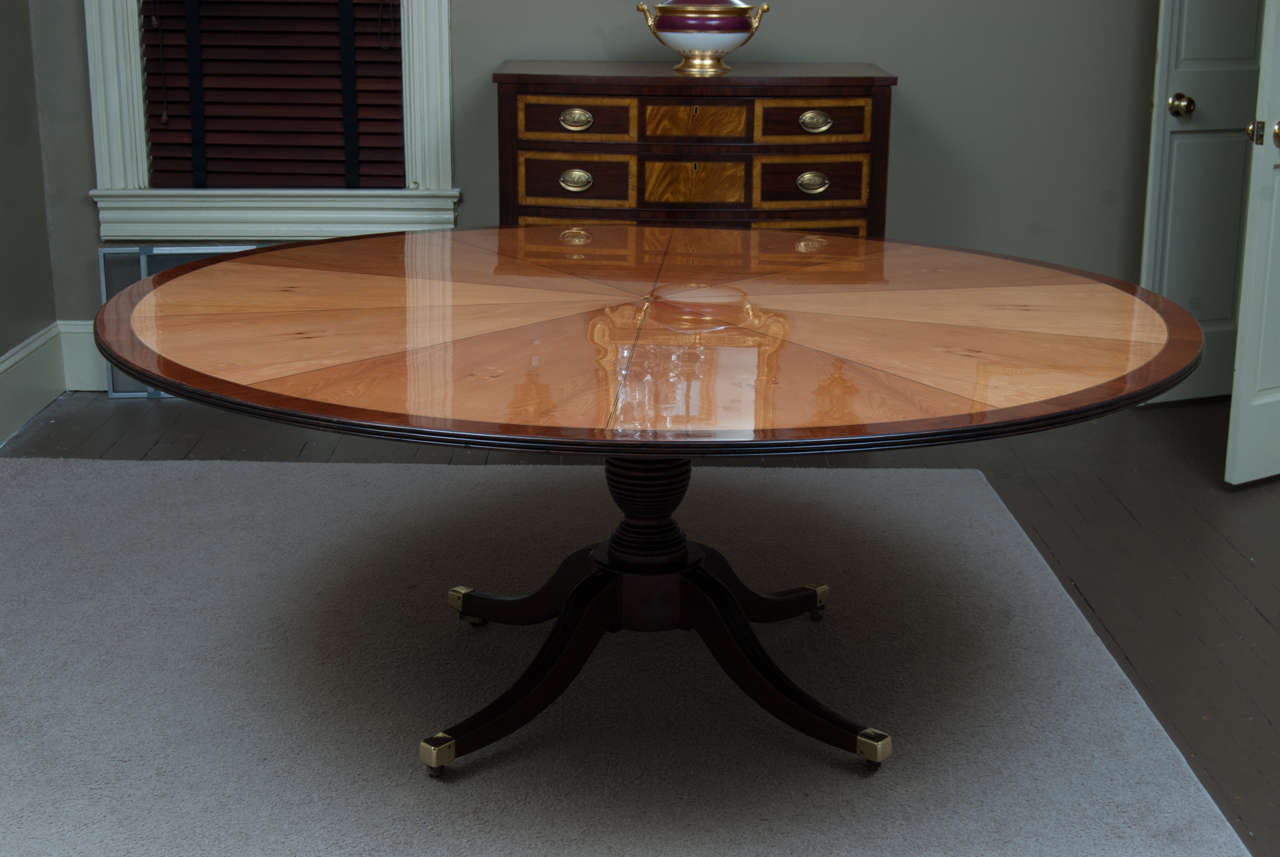 This impressive Neo-classic table originally was a large tilt-top table. Later its top was enlarged and inlaid into its current stunning form. The base has a restored French polish and original brass castors. The top is veneered in yew wood with
