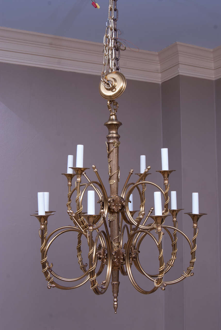 This hunting horn motif chandelier was finely cast in brass with applied ornament added. The central shaft is copied from a Roman mace with climbing vine. Includes hanging hardware, chain and ceiling cap.