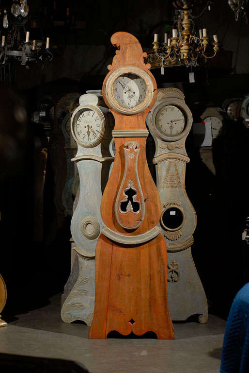This 19th century Swedish grandfather clock represents the best of informal European simplicity mixed with originality. Shining with the warm orange hue of its original paint and the added painted accent around the door, this clock features a carved