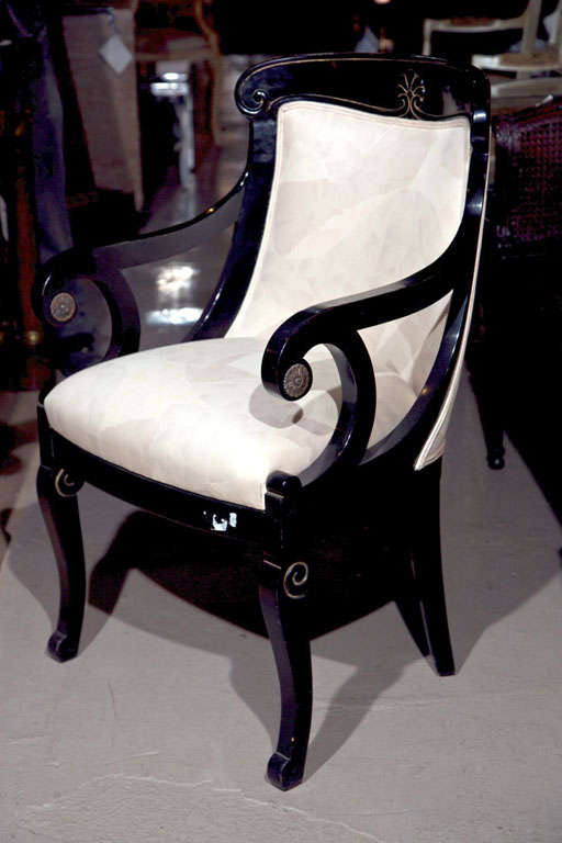 Pair of Napoleon style ebonized fauteuils, 20th century, each with domed back and scrolled arms, padded back and seat, brass accents on tip of the arms.