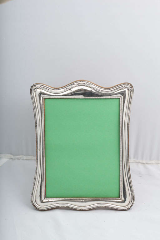 Large, sterling silver, wood-backed picture frame, Birmingham, England, 1921, Gulienetti and Co., Ltd. - makers. Measures 10 inches high (at highest point) x 8 inches wide at widest point x 5 1/4 inches deep when easel is in open position. Holds a