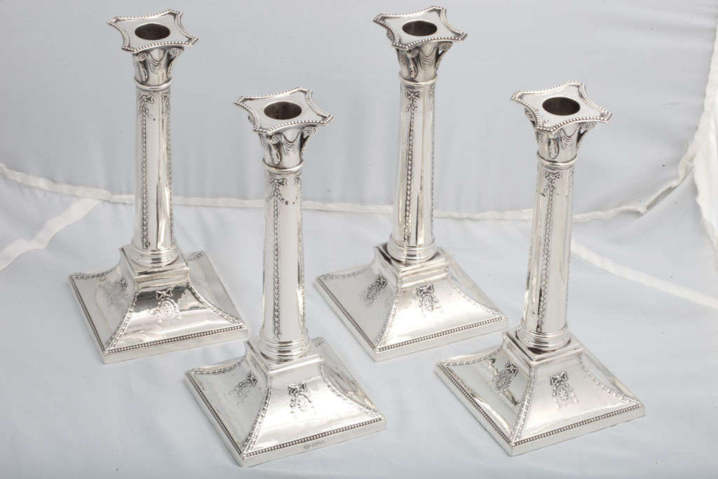 Set of four sterling silver, Neoclassical column-form candlesticks, Sheffield, England, 1918, Goldsmiths & Silversmiths Co., Ltd. -makers. Each measures: 9 inches high x a 4 inch square base. Beautifully decorated. Dark spots in photos are
