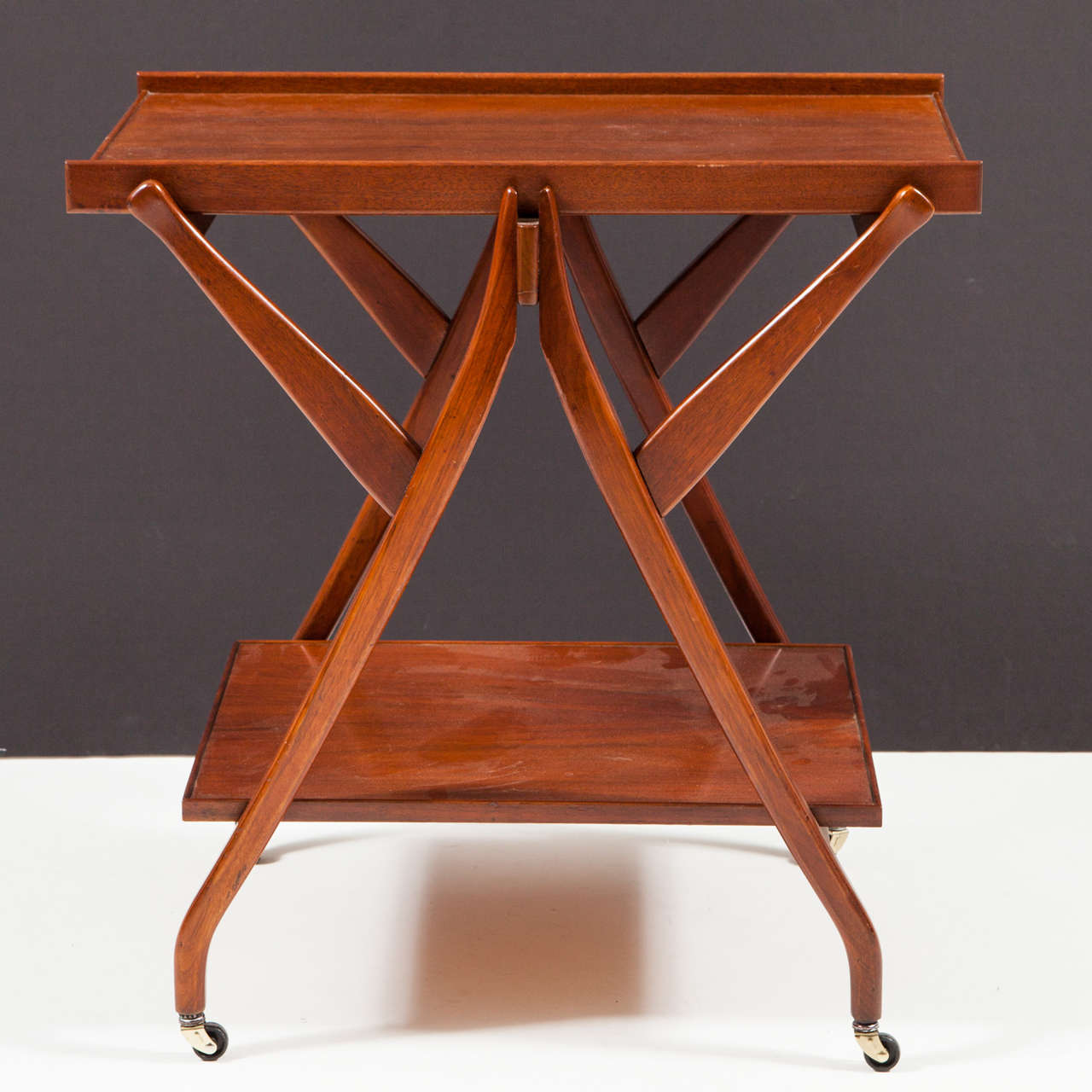 Bold geometric styling enlivens the design of this two-tier walnut serving cart by John Keal for Drexel. Recently refinished to original specification. 

This piece may be seen at our showroom, 1stDibs@NYDC, 200 Lexington Ave,Tenth Floor.