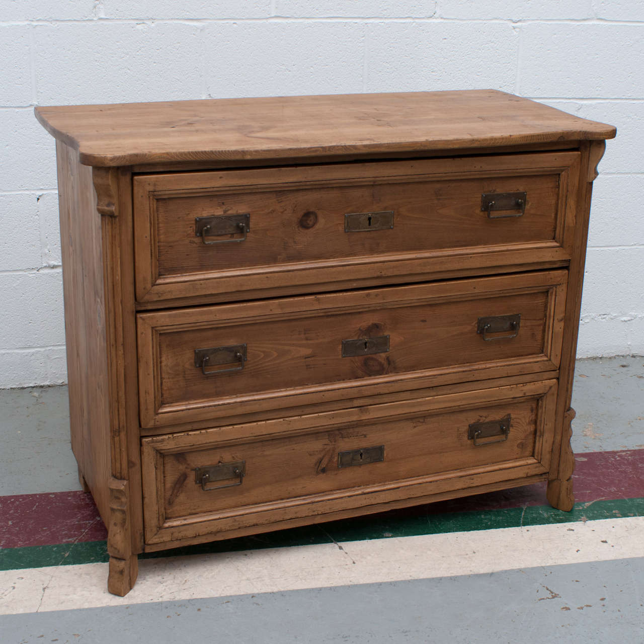 A small chest of three hand-cut dovetailed drawers with decorative corner molding and a serpentine top.