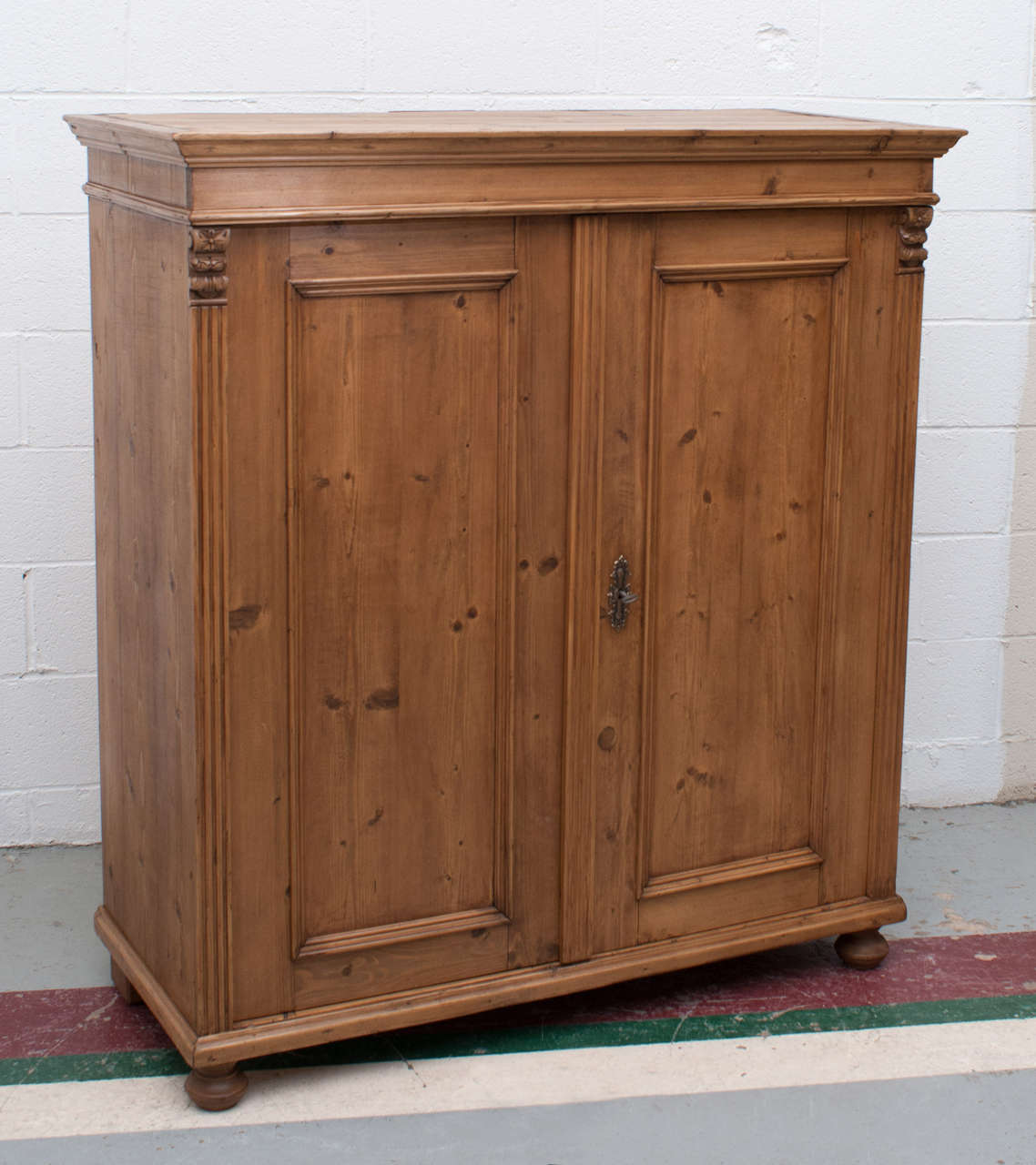 A handsome pine side cupboard with two paneled doors, fluting to the front sides and handsome carved corbels.  Exposed dovetails on the top and two replaced interior shelves.