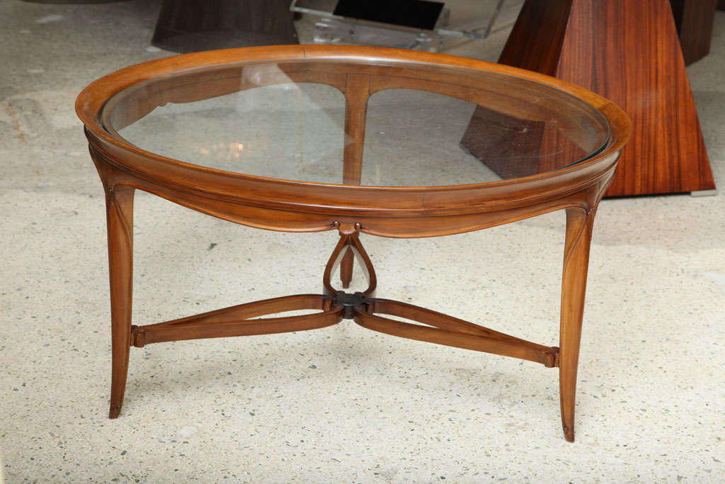 The inset glass top with finely carved mahogany frame, drapery motif on the frieze, over tapering legs, joined by a tripartite stretcher.