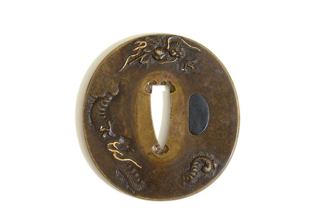 Oval brass plate carved with a sand diving dragon with gold highlights in the Edo Kinko style.