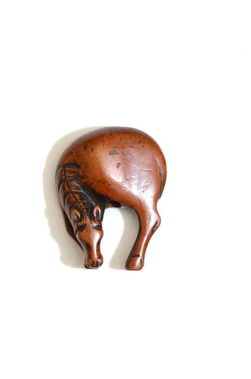 Graceful carving of a grazing horse with fine patina.