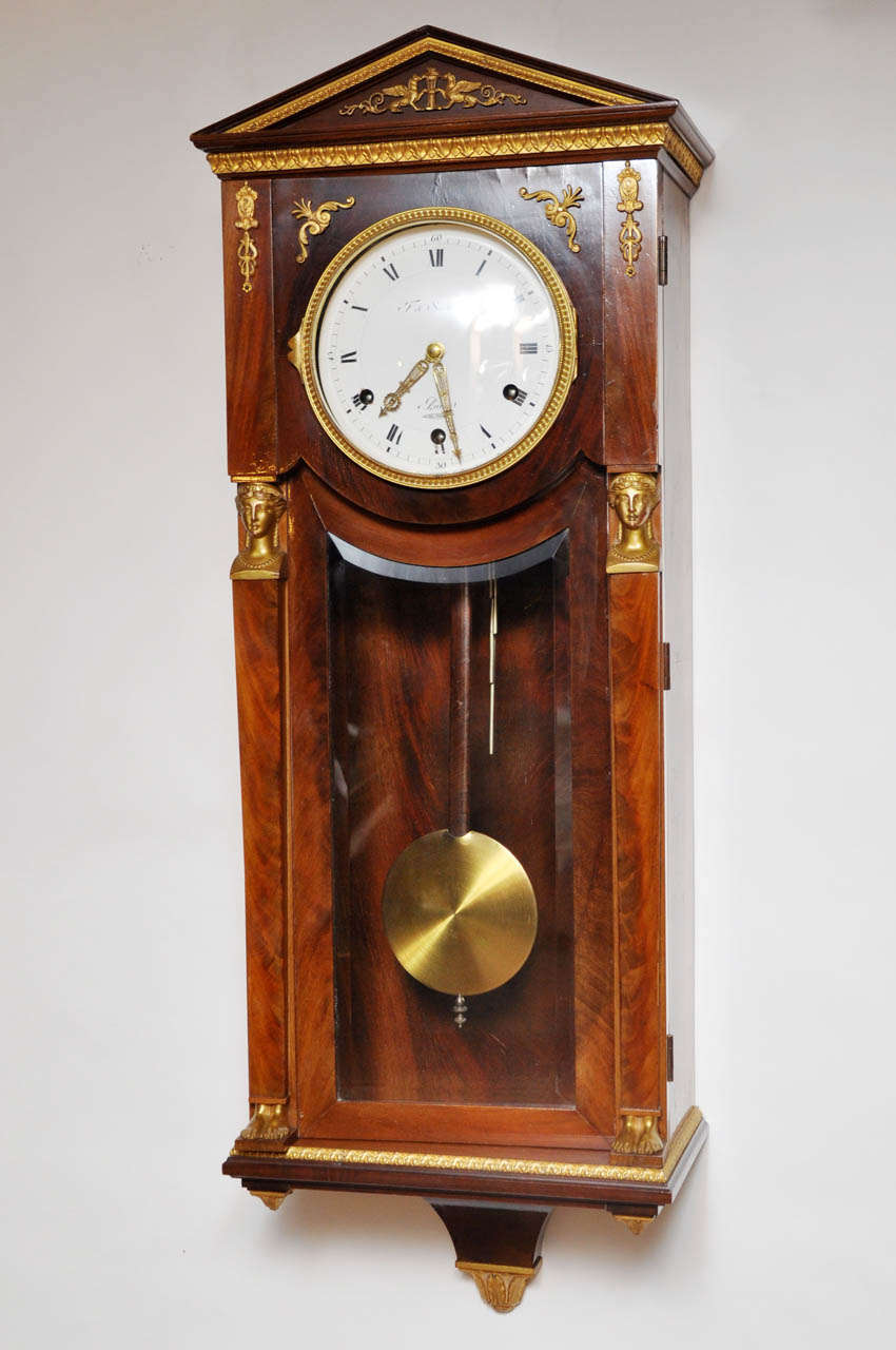 Exquisite French mahogany Empire style Westminster chime wall clock, having a French polished mahogany case with gold bronze moldings and trim on the crown, door, and platform, two gold bronze female busts are mounted to the left and right of the