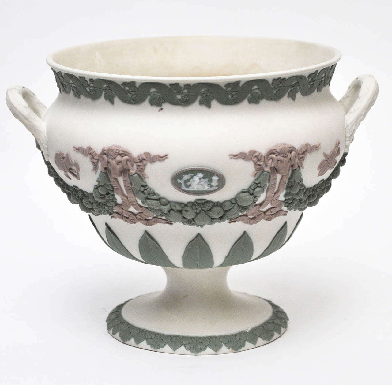 Rare, tri-colored Wedgwood jasperware urn with raised green and lavender detail on white background. Green floral ribbon design encircles the mouth, center and base of urn. The center green floral wreath is accentuated by raised lavender ram heads