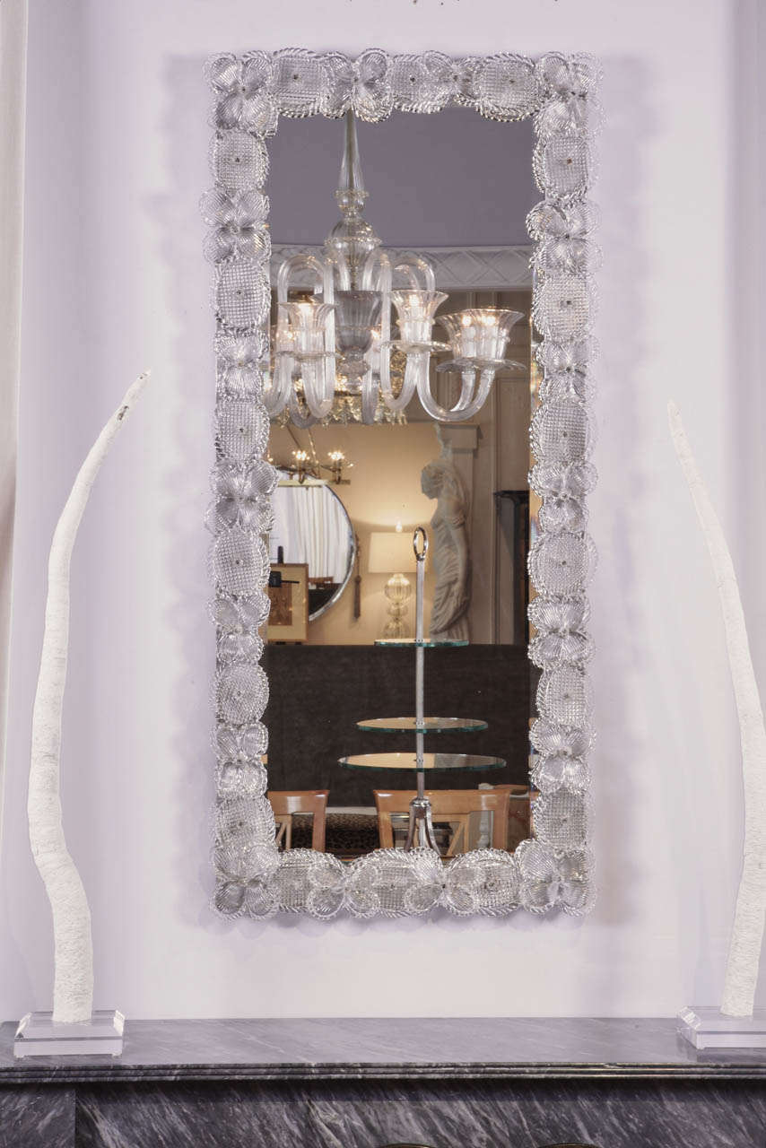 A tall antique mirror adorned with clear Murano floral glass.