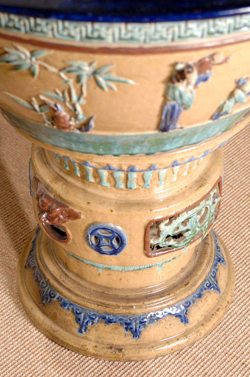 Large pottery fish bowls with applied flora and asian figures resting on pedestals. Overall celadon and gold, with a wide rim of cobalt blue.  22