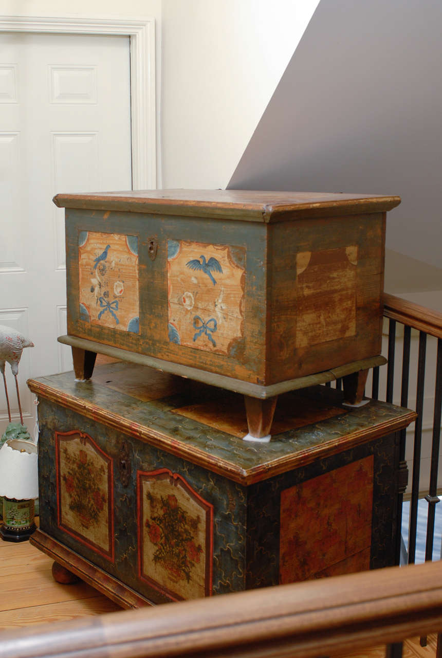 This Austrian mid-19th century painted trunk or blanket chest features a simple yet elegant appearance. A rectangular top sits atop a lovely painted body. The front of the trunk is decorated with blue birds and ribbon motifs, symmetrically and