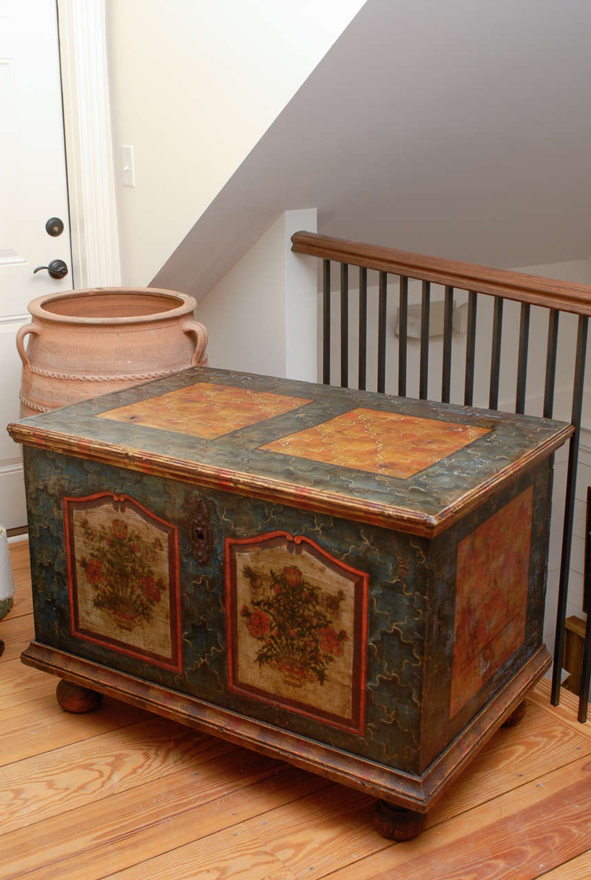 An Austrian Bohemian wooden trunk painted with jigsaw patterns from the mid-19th century. This painted trunk, which probably used to be a marriage chest, features a simple yet elegant Silhouette. A rectangular top sits above a blue painted body with