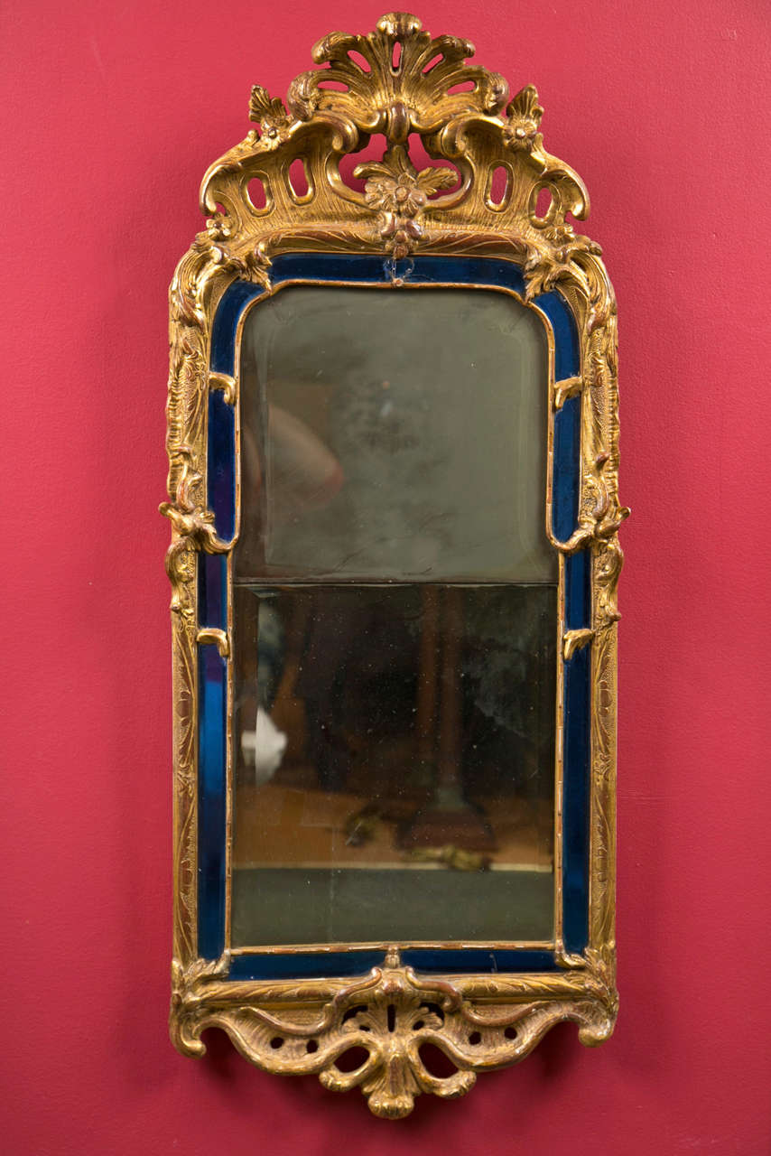 A late 18th century continental giltwood mirror having shaped bevelled cobalt mirrored conforming border. Some restorations.