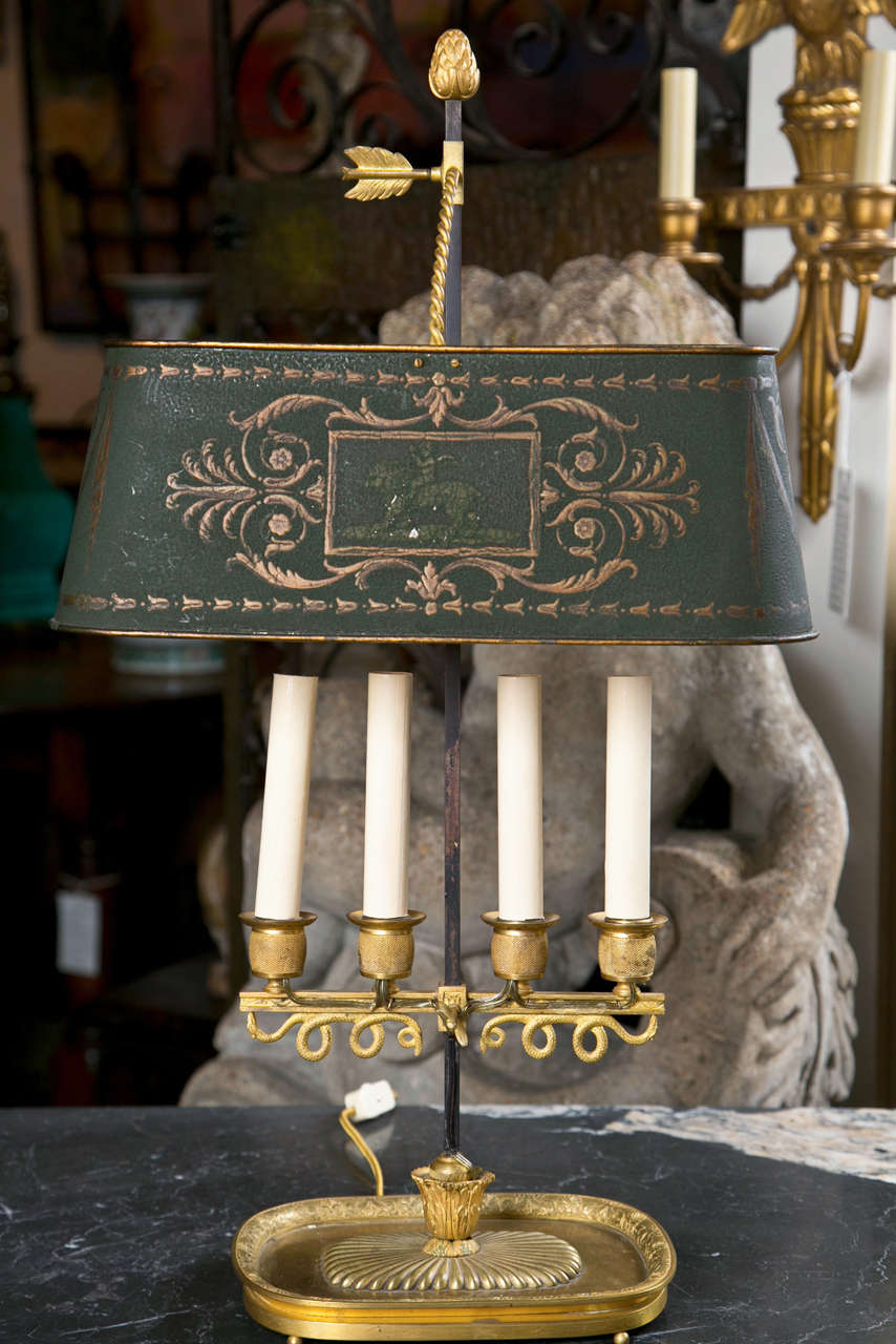 Lampe bouillotte en bronze doré de la Baltique, décorée de tole peinte et de polychromie.  La base rectangulaire en forme d'anthemion, moulée et godronnée, est surmontée d'une crémaillère à enroulement de serpents et de feuillages, avec cinq buses