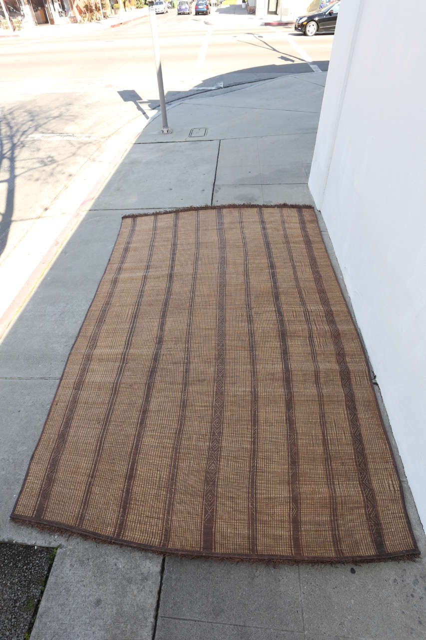 Moroccan Tuareg leather mats are made of dwarf palm tree fibers and hand-woven with leather stripes, this are great to use indoor or outdoor, beautiful brown earthtone colors. This vintage mid century rugs are made in the desert of Morocco near