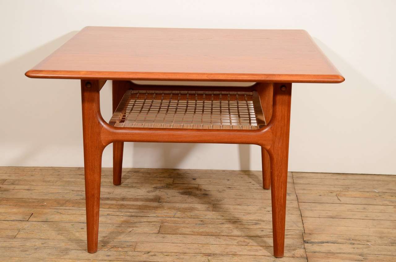 A Danish vintage end table, produced circa 1960s by Trioh, in wood frame, with a second tier shelf in woven rattan, on tapered legs. Markings include maker's stamp, beneath the table. Very good condition, with age appropriate wear.