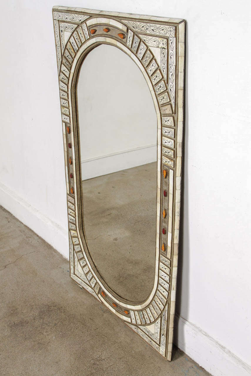 Moroccan mirror inlaid with camel bone and brass embossed metal, intricately carved with classic elements of Moorish design such as geometric form using symmetry and inlaid decoration. This style is based on the architecture and design principles of