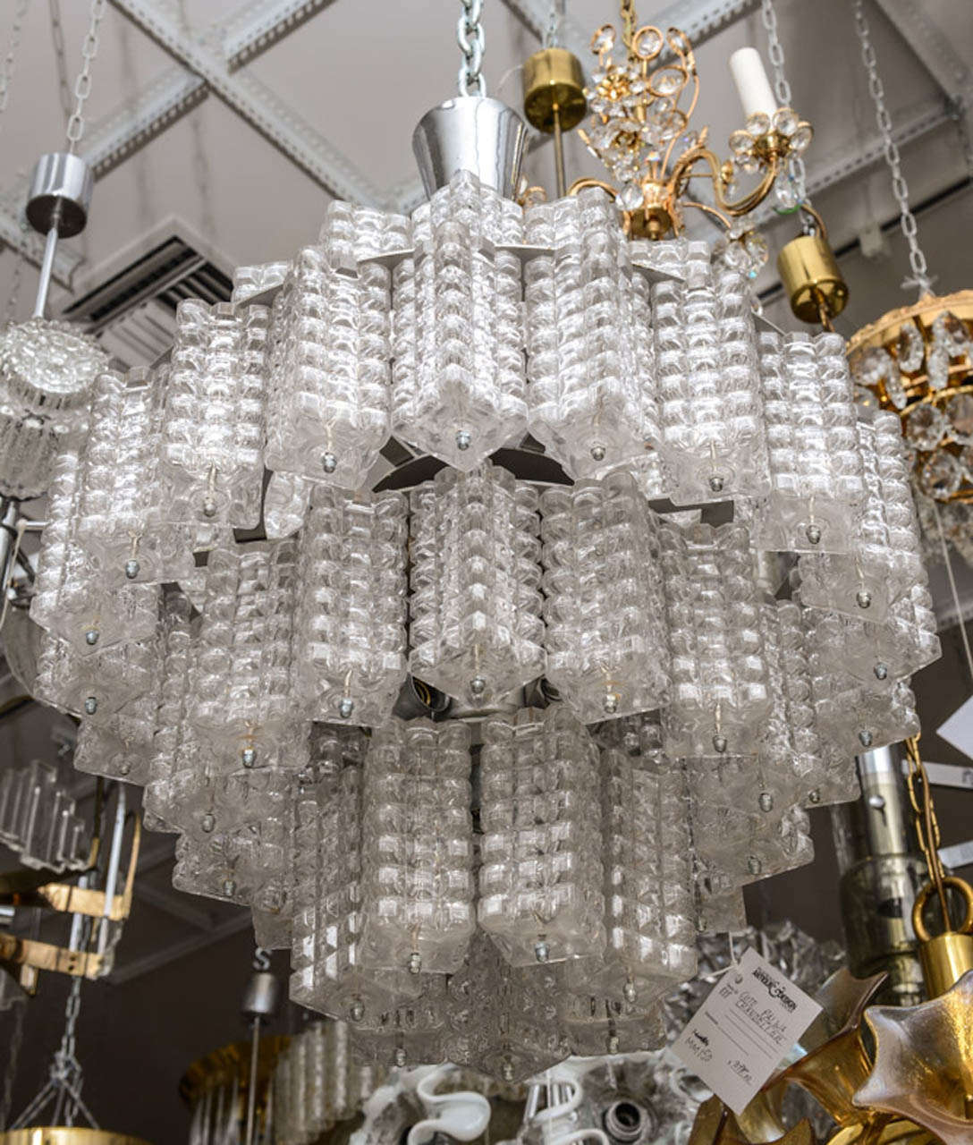 High polished chrome Kalmar chandelier features 4 tiers of clear single hung textured rectangular glass columns.