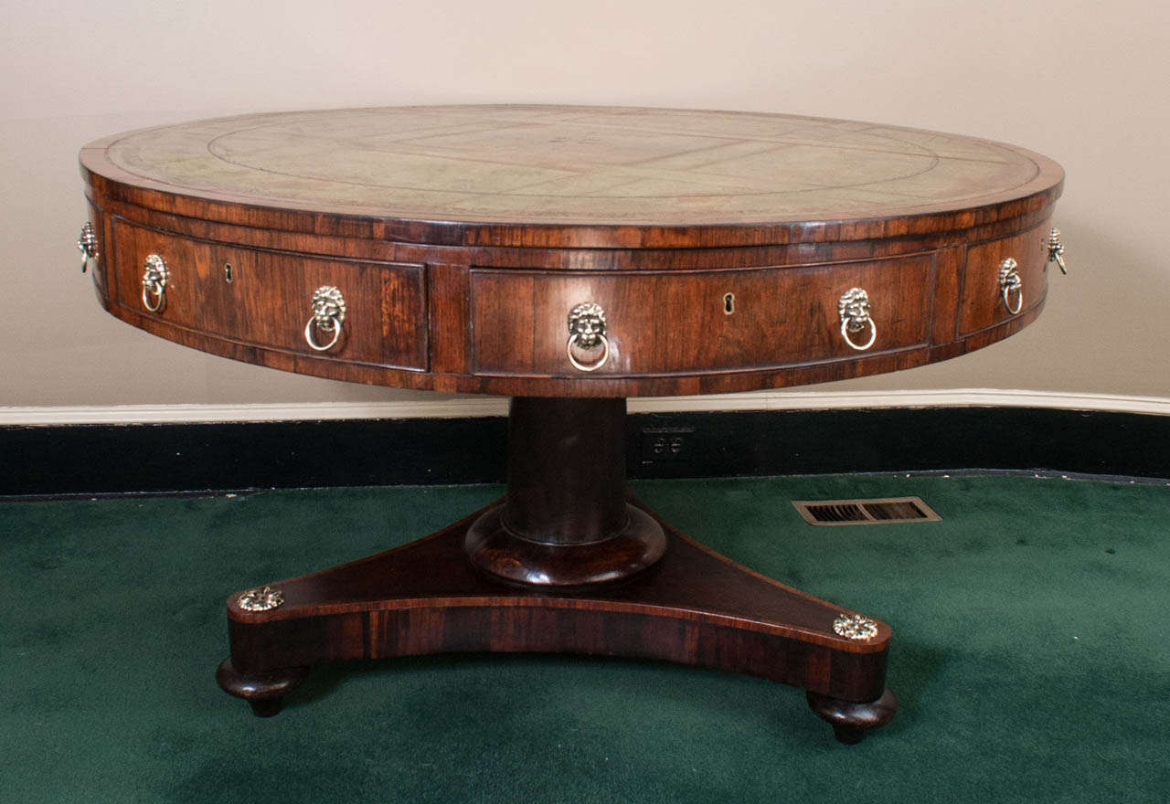 This large drum table has four working drawers and four faux drawers. The leather top has been on the table for more than 100 years and has an exceptional patina, much of its gold leaf embossed decoration is clearly visible.