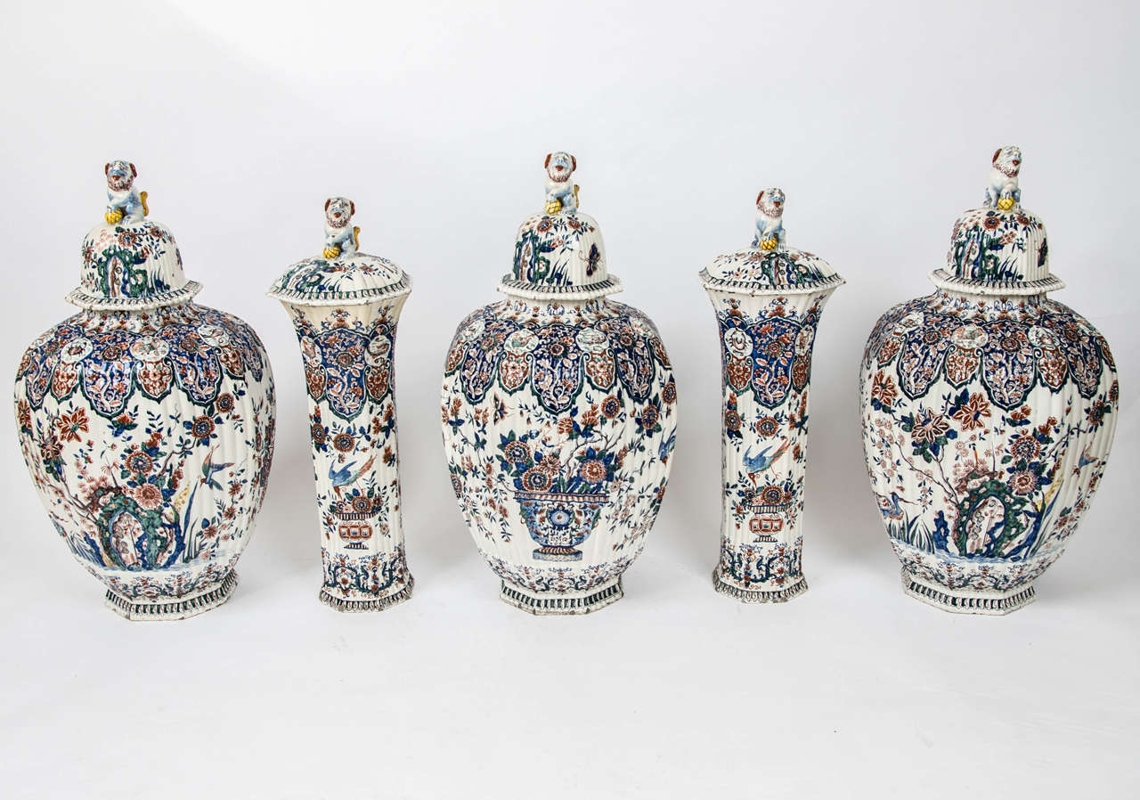 A massive garniture of five Delft 19th century polychrome painted vases and covers, with floral decoration and lion topped covers.