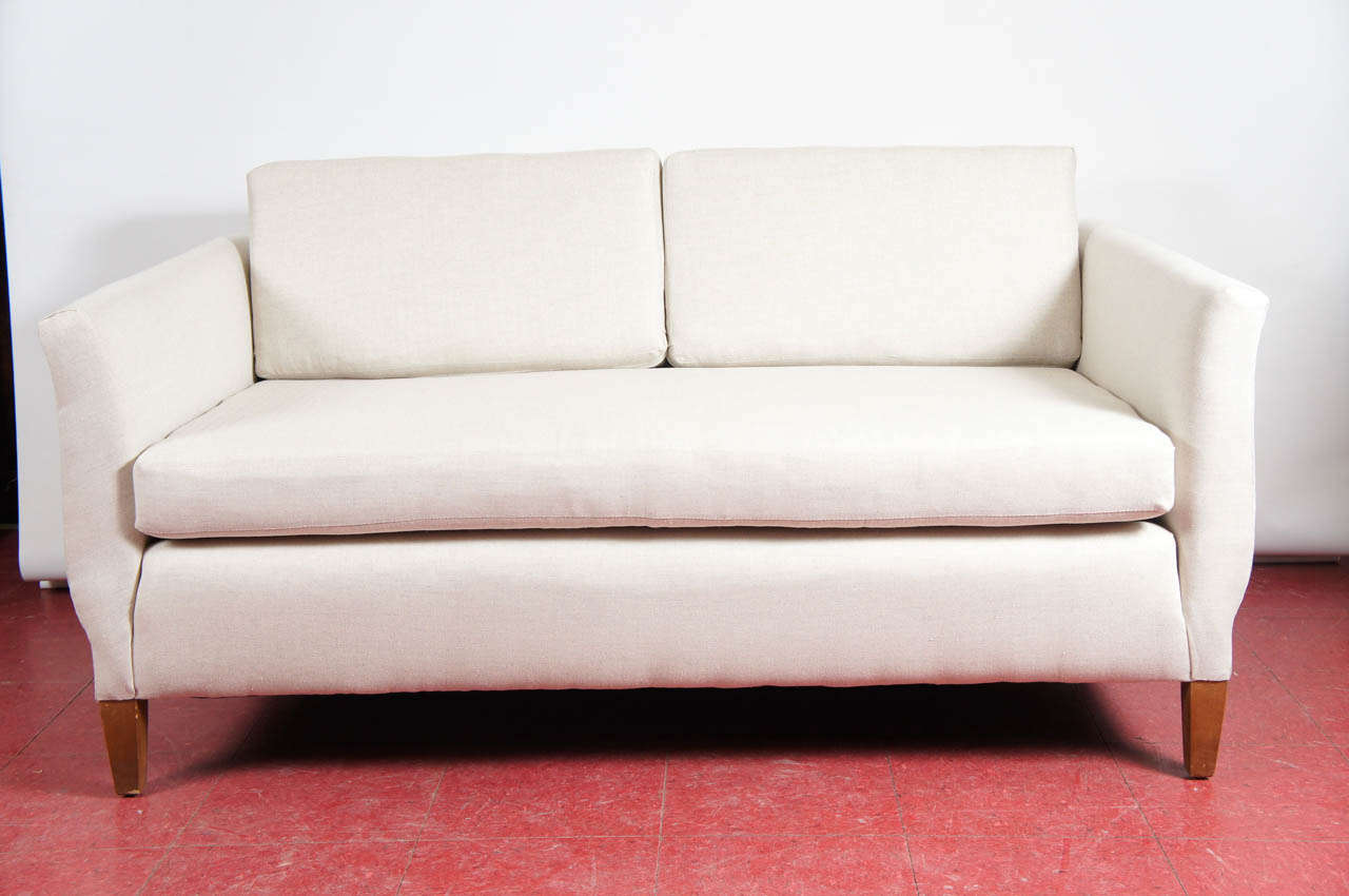 Matching ivory linen upholstered settee or love seats with gracious curves on outside of the arms.