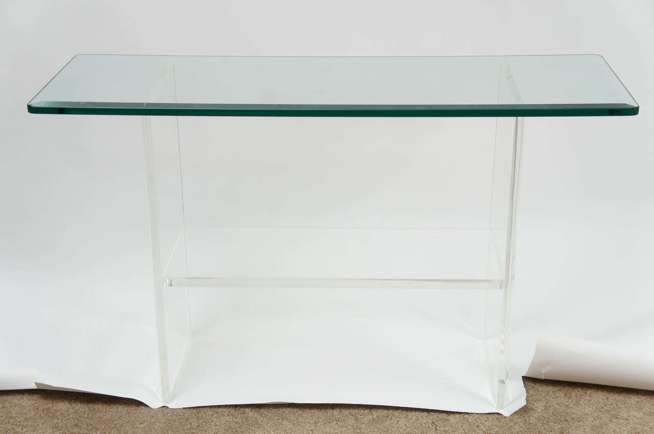 Lean and lovely, this 1980's console makes an elegant, barely visible  statement. The lucite base is in great condition, as is the beveled glass top. Whether you're considering for behind the sofa or in the entrance foyer, the piece blends into the