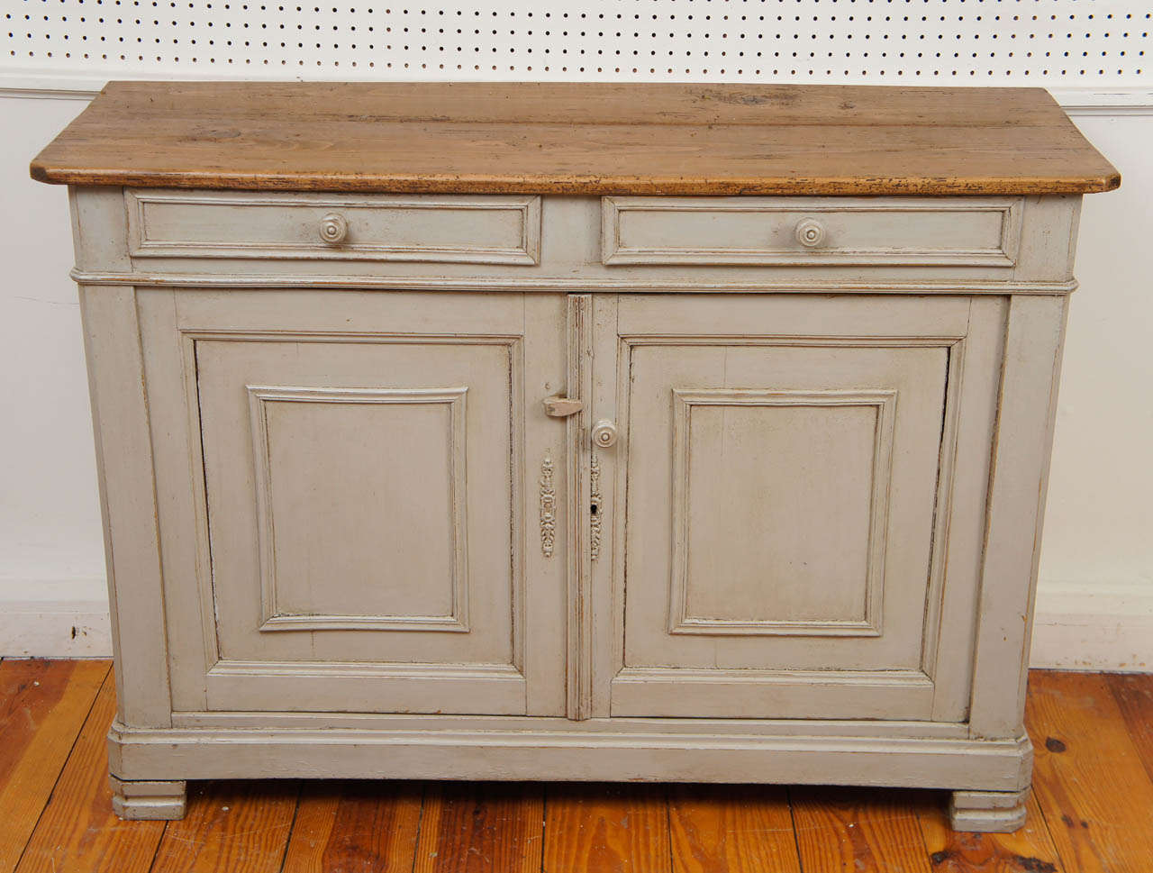 We love a scrubbed pine top along with a gray painted base. They are a handsome combination. Once again the combo does not disappoint on this 1870 French server. The paneled doors and trimmed drawers are delightful. There are two drawers and two