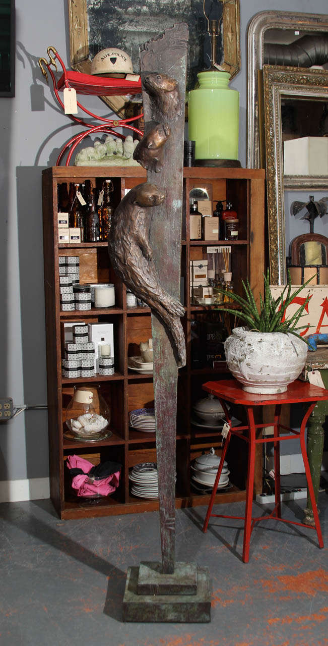 Tall bronze sculpture by Georgia Gerber with 3 otters.