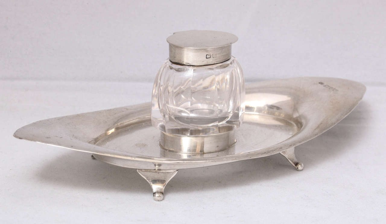 Edwardian sterling silver and crystal footed inkstand, the inkwell anving a sterling silver hinged lid, Chester, England, 1906, William Naylor, maker. Lovely oval sahap; glass of inkwell is nicely panel-cut. Measures: 7