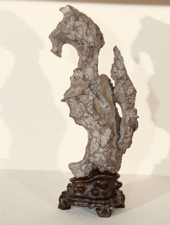 Chinese Lingbi or scholar's rock of dramatic form, with original carved wood base. Collected in China and brought to Japan at the turn of the century, stones of this type were highly sought after and placed on scholar’s desks as contemplative