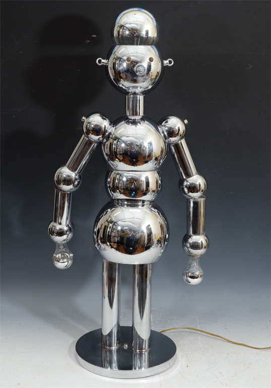 This Italian chrome robot lamp was designed by Torino in the 1950s.  Head and hands light independently via the three way light switch which serves as the nose. Lucite eyes glow when illuminated.