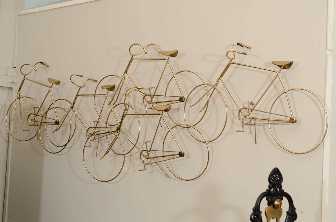 A vintage wall mounted sculpture of a group of bicycles. The piece is in brass and signed Curtis Jere, 1973