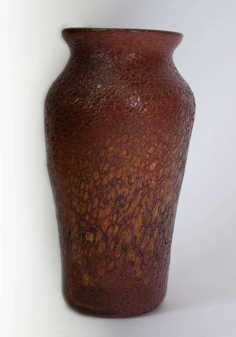 Made in England by the Stourbridge Glassworks of Stevens and Williams, this tall, shouldered vase is made of deep red crystal glass with a textured volcanic effect.