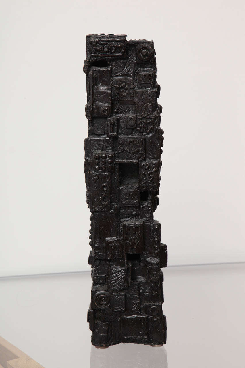 Cast bronze, column-form sculpture with applied letters, symbols and geometric shapes. William Tarr lived and worked for most of his career in New York City and worked primarily in welded steel. This piece is typical of much of his work during that