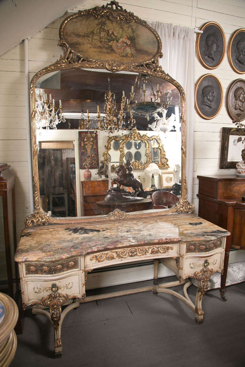 The mirror topped by an oval painting of lovers in a  garden setting. The mirror separate from the   dressing table. Cream painted  body with highlights of color on the drawer fronts, legs and feet. The mirror frame of  carved gilt wood.
Stretchers