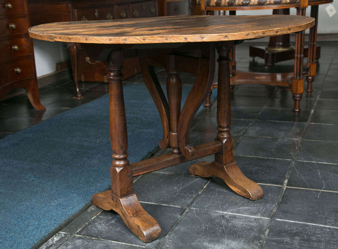 With the remnants of its original oilcloth cover, this little table in poplar and fruitwood could probably tell a tale or two. The height of 26.5” is just right for the hand to fall and comfortably grasp the stem of a glass. Used quite often at a